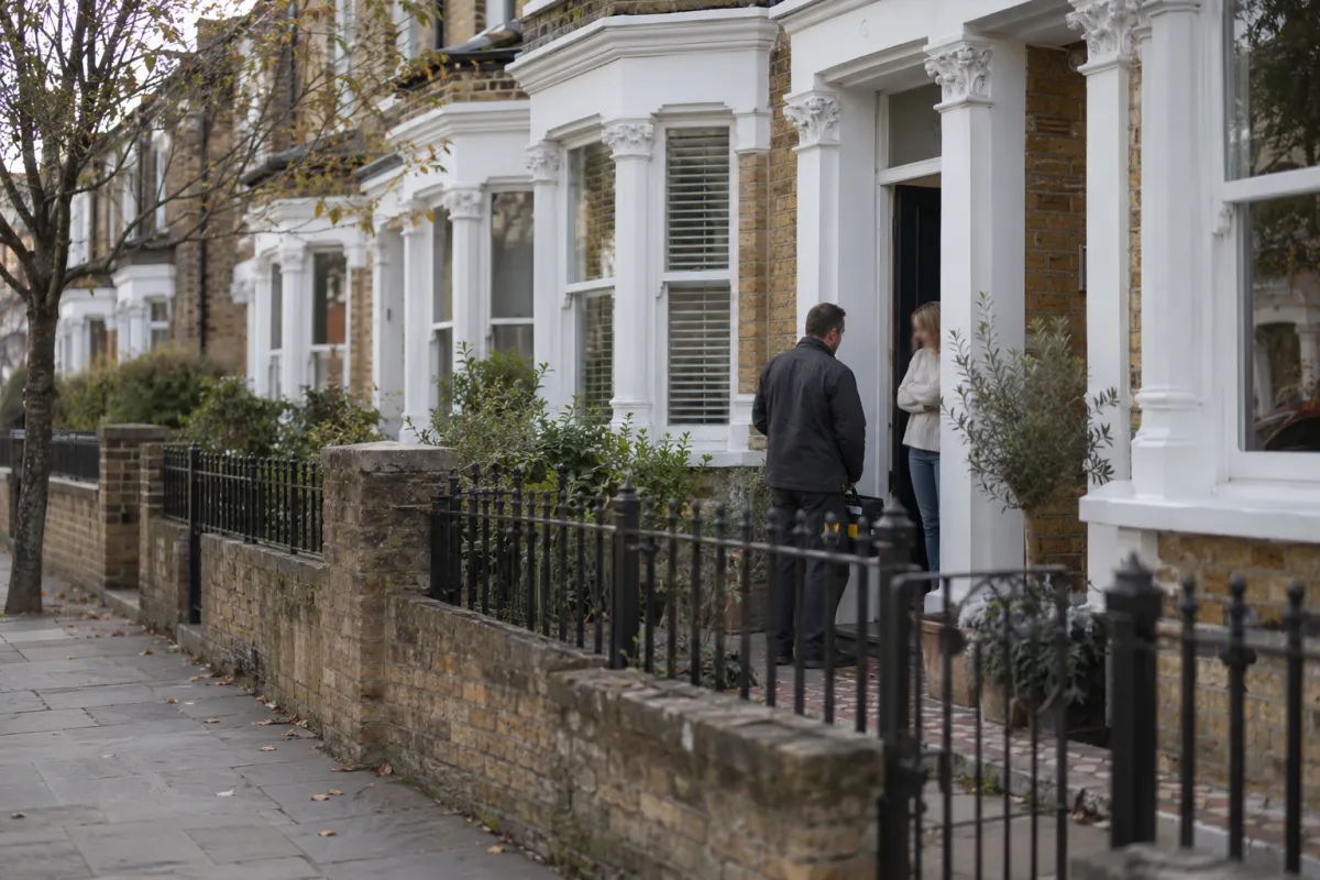 Pest control technician talking with a homeowner at the door of a terraced house