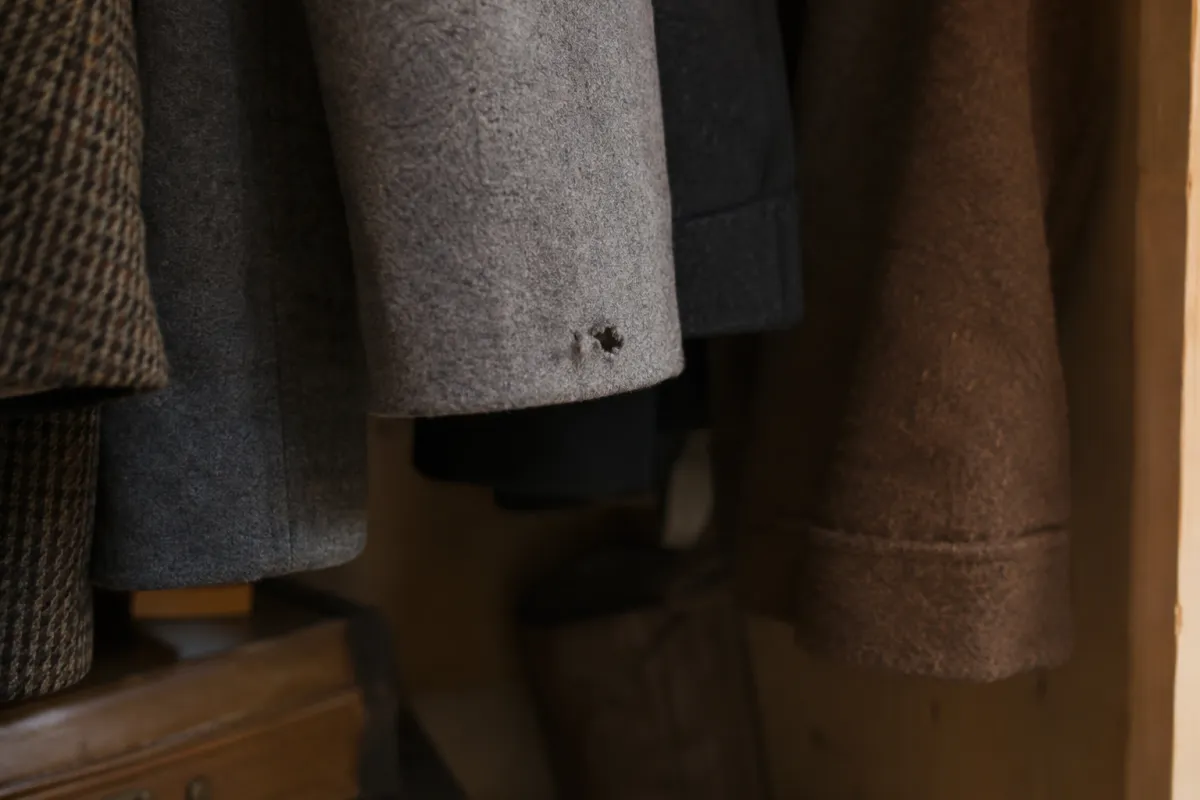 Wool coats in the back corner of a wardrobe, with a small eaten patch on one hem